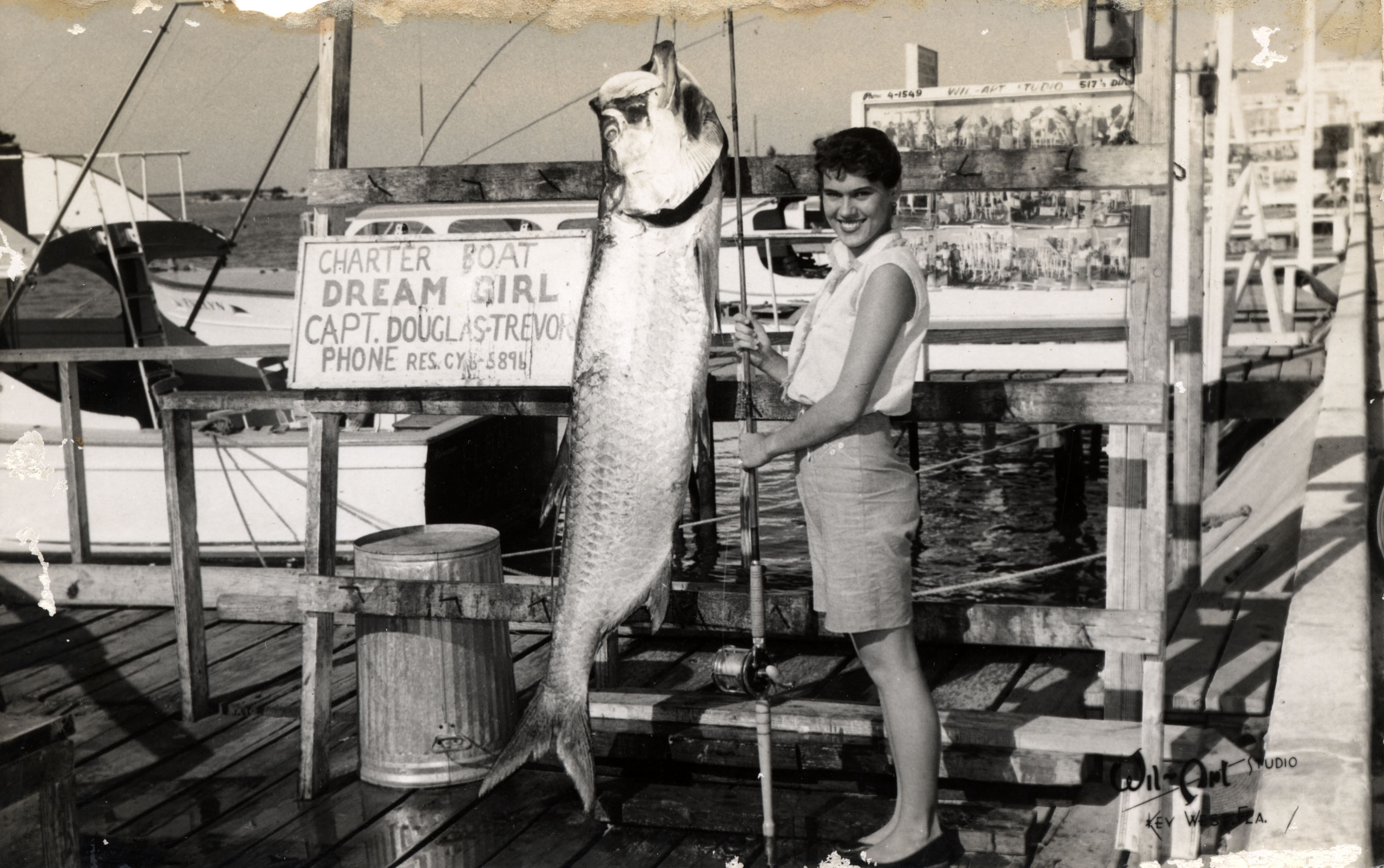 a young woman stands by a fish equal to her size