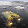 A yellow remotely operated underwater vehicle, or ROV, at the surface of the water. 