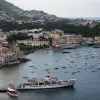 A photo of a seaside town with boats docked in the harbor and buildings along the shore. 