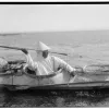 a hunter throws a harpoon from the cockpit of his kayak