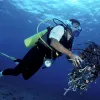 A diver cares for the reef by cleaning up discarded fishing gear and garbage.