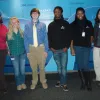 Students studying climate change pose for a photo against a wall.