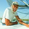 A Gulf Coast resident sits on his boat, smiling for the camera. 