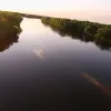 An aerial shot of a tree-lined section of the Mississippi River at sunset. 