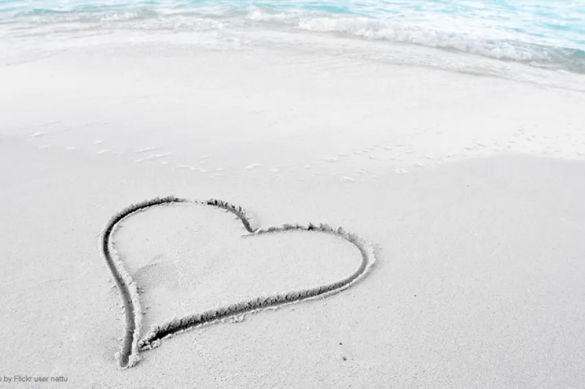 A photo of a beach with a heart inscribed in the sand.