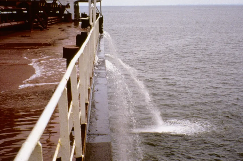 A large ship flushes water from its ballast tanks while at sea