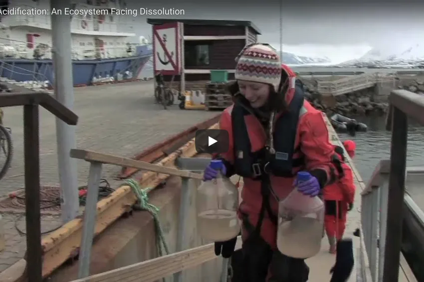 A screenshot from the video with a scientist walking up a dock. 