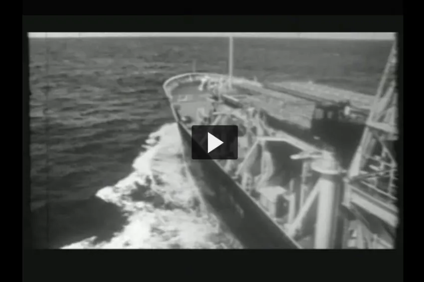 A screenshot from the video "Integrated Ocean Drilling Program" showing the front of a research vessel moving through water. 