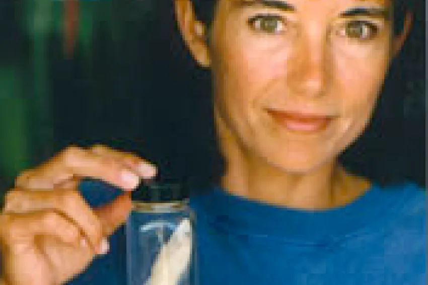 Carole Baldwin holding a preserved fish in a jar.