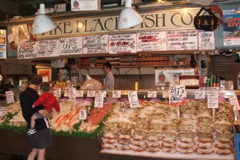 Seafood vendor at historic Pike Place Market in Seattle, Washington (USA). The market draws both shoppers and gawkers who come to watch the gregarious crew of fishmongers.