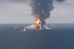 Fire fighting ships surround the burning Deepwater Horizon oil rig, shooting water at it to put out the flames.