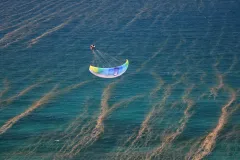 A paraglider flies over the ocean 