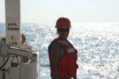 a woman works on a ship in a hard hat and vest
