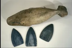 During whale hunts, this carved whale box stored harpoon blades like the three shown beside it.