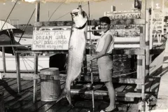 a young woman stands by a fish equal to her size