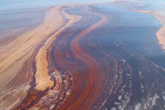 a ripple of rust colored oil in the ocean