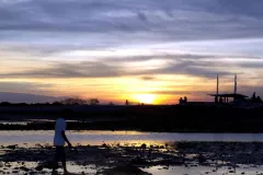 The sun sets over Sanur in Bali, Indonesia during low tide.