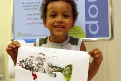 A young visitor holds up his painted fish Gyotaku fish print at the Smithsonian's National Museum of Natural History
