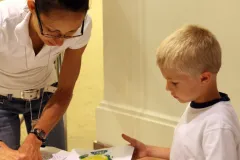 A teacher and a young boy paint a fish mold to create a Gyotaku style print