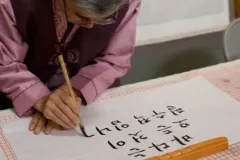 A photo of calligrapher Myoung-Won Kwon writing an ocean-themed message. 