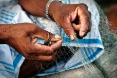 a closeup of hands mending a fishing net