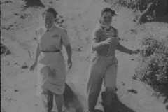 two young women gleefully race down a sandy hill