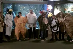 Students in marine life costumes pose in an aquarium.
