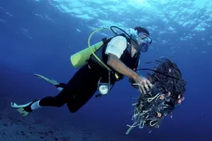 A diver cares for the reef by cleaning up discarded fishing gear and garbage.