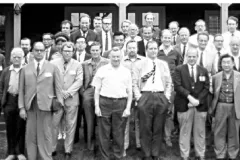 a black and white photo of a group of men and one black woman