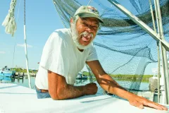 A Gulf Coast resident sits on his boat, smiling for the camera. 