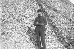 A longshoreman standing in front of a large pile of oyster shells on waterfront pier in Atlantic City in 1910.