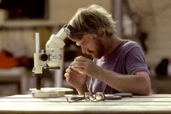 a scientist peers through a microscope