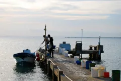 a man tends a small boat at the end of a dock