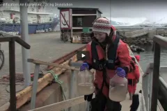 A screenshot from the video with a scientist walking up a dock. 