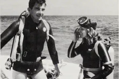 a man and a women in scuba gear on the deck of a ship