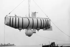 a massive submersible hangs from a crane