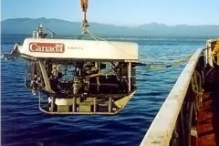 a robotic sensor hangs over the side of a ship