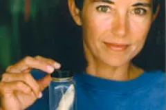 Carole Baldwin holding a preserved fish in a jar.