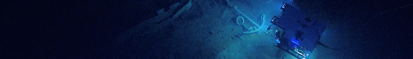 A remotely-operated-vehicle explores the sea floor in dim light. 