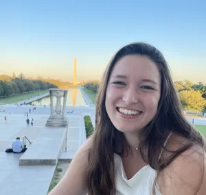 a young woman sits with the Washington monument in the background