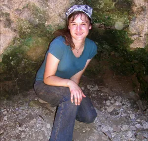 Anne Wiley kneeling in a cave.