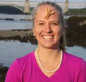 Danielle Hall smiling at the camera with a sea star on her forehead.