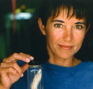 Carole Baldwin holding a preserved fish in a jar.