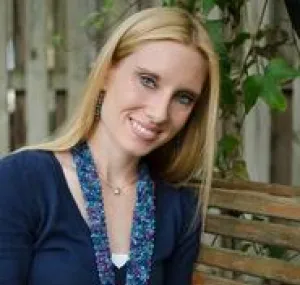 Grace Costantino smiling at the camera while posed over a notebook. 