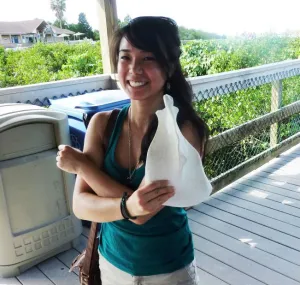 Megan Chen on a deck with bushes in the background.
