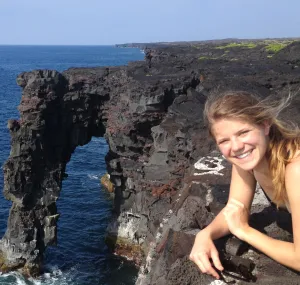 Laura Brodbeck leans on a rock overlooking the ocean.