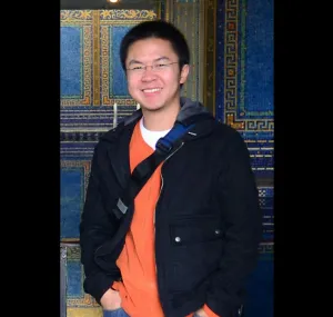 Laurence Yeung standing with a bag and smiling at the camera.