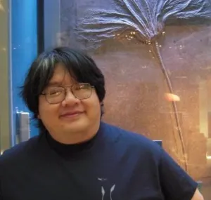 Chris Mah stands in front of an ocean fossil. 