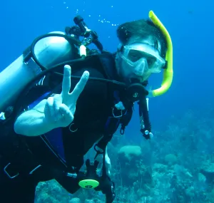 Phil Colarusso gives a peace sign while diving underwater.