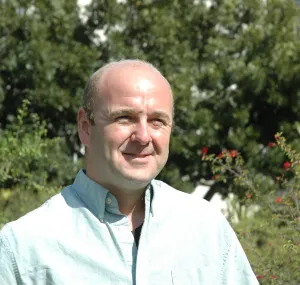 Rob Edwards smiling at the camera with trees in the background.